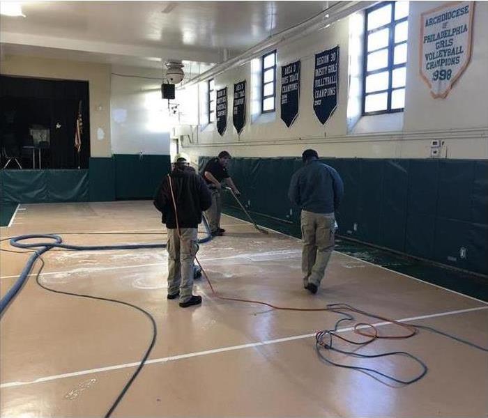 workers with vacuum extractor, cleaning water damage inside a building